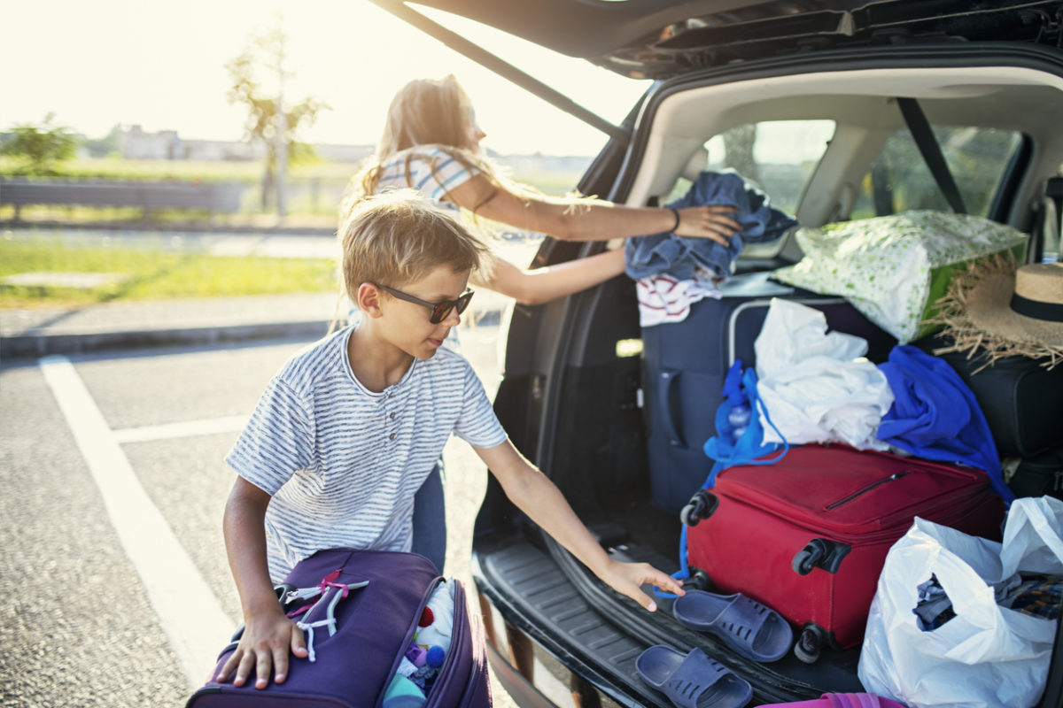 Kids helping to pack the family car for road trip.