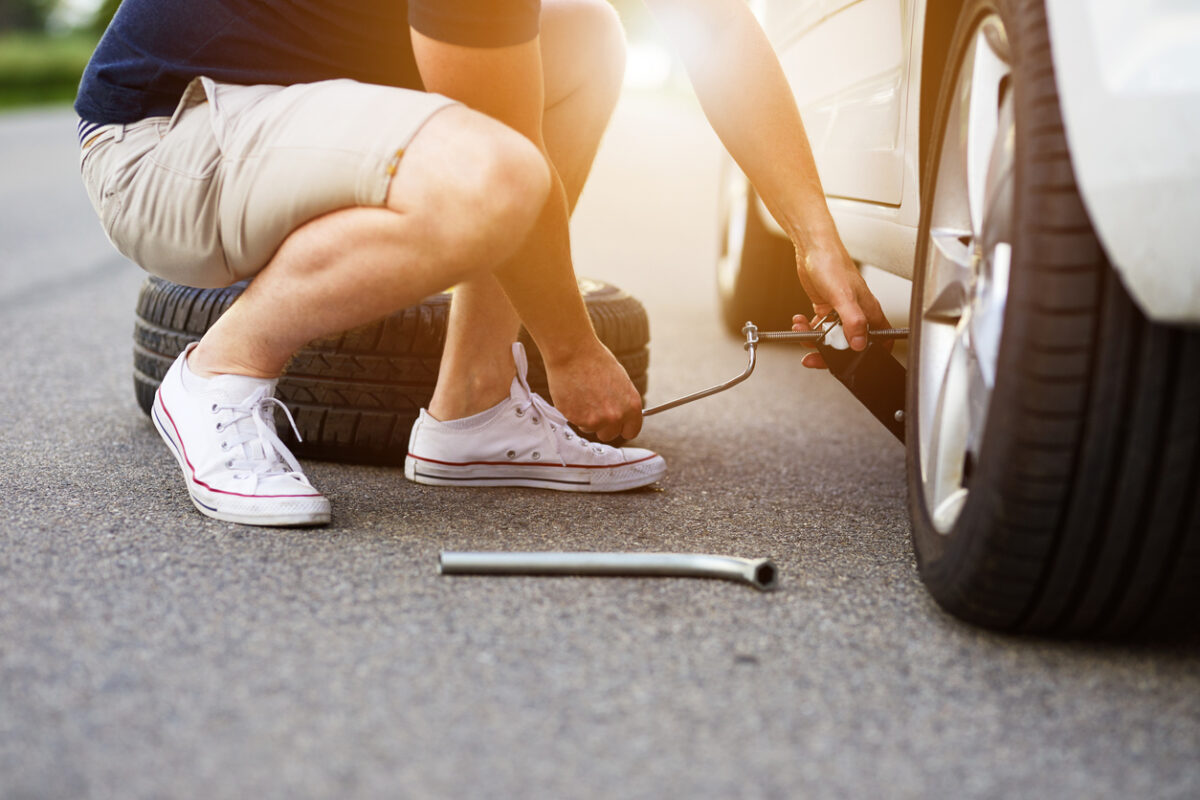 The man changes the tire on his car