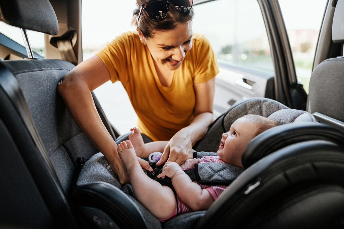 Mother Putting Baby in Child Car Seat