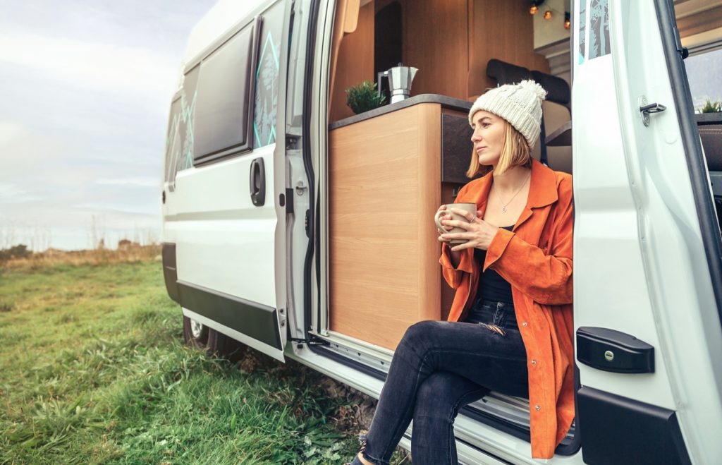 Woman Drinking Coffee Sitting in Door of Converted Campervan